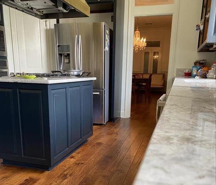 After photo of kitchen with blue cabinets, granite, and hardwood flooring