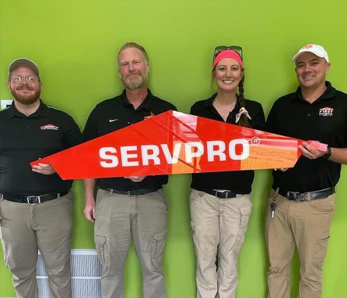 SERVPRO employees holding up SERVPRO sign